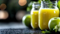 Fresh yellow smoothie in glass mason jars with green apples on dark background with bokeh lights, healthy detox drink for wellness and diet.