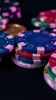Colorful poker chips stacked on dark casino table with blurred gambling background for entertainment and gaming concepts.