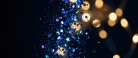 Abstract blue glitter particles with golden bokeh lights creating magical sparkle effect on dark background for luxury design projects.