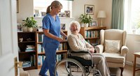 Professional caregiver in blue scrubs assisting elderly Caucasian woman in wheelchair at comfortable home living room with bookshelves and natural lighting.