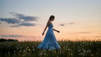Woman in blue dress walking through wildflower field at sunset, enjoying nature and outdoor freedom during golden hour evening time.