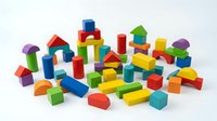 Colorful wooden building blocks set with various geometric shapes including cubes, cylinders, triangles and arches scattered on white background for educational play.