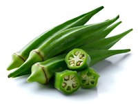 Fresh green okra pods with sliced cross sections showing star pattern inside, isolated on white background for food and cooking concepts.
