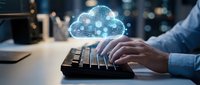 Professional typing on keyboard with glowing cloud computing icons floating above, representing digital transformation and remote work technology solutions.