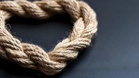Twisted natural jute rope macro shot showing detailed fiber texture and braided pattern against dark background, suitable for marine and craft design projects.