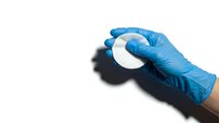 Hand in blue medical glove holding white petri dish for laboratory research and scientific testing on white background isolated for design use.