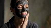 Young woman applying charcoal face mask for skincare routine, spa treatment and beauty wellness at home with natural cosmetic products.