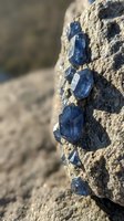 Blue mineral crystals embedded in rough stone formation with natural geological texture and earthy tones for mining and earth science concepts.