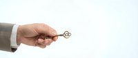 Businessman hand holding golden key against white background, symbolizing success, opportunity, solution, and unlocking potential for business concepts.