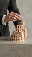 Businessman hands protecting wooden blocks with arrows and targets symbolizing business growth strategy and goal achievement in corporate environment.