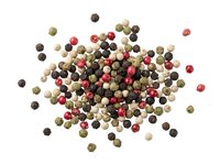 Mixed peppercorns isolated on white background, including black, pink, white and green pepper varieties. Culinary ingredient for cooking and seasoning.