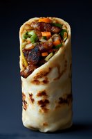 Grilled flatbread wrap filled with tender meat, fresh carrots, and green peppers on dark background. Close-up food photography shows texture and layers.
