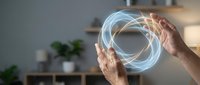 Hands holding glowing circular holographic interface with swirling light effects in modern home interior for futuristic technology concepts.