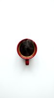 Red ceramic coffee mug with steaming hot black coffee viewed from above on white background isolated for design use.