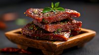 Glazed pork belly slices stacked on wooden serving board, garnished with fresh herbs and spices against dark background. Rich caramelized coating glistens.
