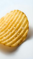 Golden crispy ridged potato chip with sea salt crystals isolated on white background for snack food packaging and culinary design projects.