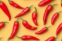 Fresh red chili peppers arranged in pattern on yellow background, bright and vibrant composition showing multiple whole peppers with green stems.