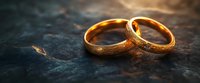 Two golden wedding bands with textured surfaces rest on a dark stone surface, symbolizing eternal love and commitment for marriage ceremonies and engagement announcements.