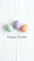 Three pastel speckled Easter eggs in mint, lavender, and peach on white linen with Happy Easter text, minimal flat lay greeting card.