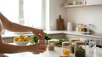Woman preparing healthy meal with fresh herbs and spices in modern kitchen, cooking nutritious food with natural ingredients for wellness lifestyle.
