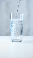 Fresh sparkling water pouring into clear glass with bubbles on white surface for health and hydration concepts.