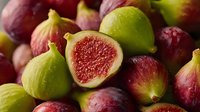 Fresh ripe figs with vibrant red flesh and green purple skin arranged together, showcasing natural organic fruit textures for healthy eating concepts.