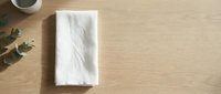 White napkin or paper towel on wooden table with coffee cup and eucalyptus leaves, flat lay composition for kitchen and dining design projects.