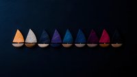 Colorful wooden sailboats arranged in rainbow sequence on dark background, minimalist composition shows gradient color transition from orange to red, artistic still life.