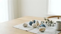 Minimalist Easter eggs in neutral tones arranged on linen table runner with eucalyptus branch and ceramic mug for spring home decor styling.