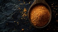 Aromatic spice blend with red chili flakes and ground seasonings in rustic wooden bowl on dark stone background, dramatic food photography lighting.