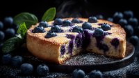 Fresh blueberry cheesecake with powdered sugar and mint leaves on dark background, slice cut to show creamy texture and fruit filling. Food photography.
