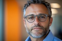 Professional middle-aged businessman with glasses and beard in modern office environment for corporate communications and leadership content.