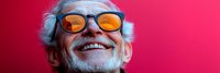 Cheerful elderly Caucasian man with gray hair and orange-tinted glasses smiling broadly against vibrant pink background for lifestyle and wellness concepts.