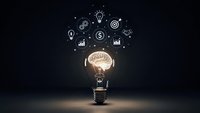 Creative lightbulb with glowing brain inside surrounded by business icons on dark background representing innovation, ideas, and entrepreneurial thinking.