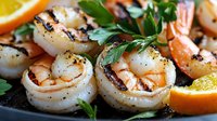 Grilled jumbo shrimp and scallops with fresh herbs and citrus on dark background, close up view of seafood appetizer garnished with parsley and orange slices.