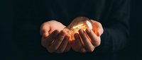 Hands holding glowing light bulb symbolizing innovation, creativity, bright ideas, inspiration and entrepreneurship for business concepts.