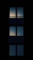 Dark silhouette of three vertical windows against evening sky, creating minimalist geometric pattern with gradual light transition from dusk to darkness.