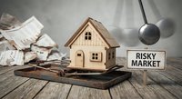 Wooden house model in mouse trap with risky market sign and scattered money, representing dangerous real estate investment and financial risk concept.