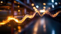 Glowing golden light trail with sparkling particles flowing on dark blurred bokeh background, creating magical energy wave effect for abstract designs.