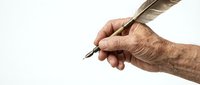 Elderly hand holding vintage feather quill pen for writing calligraphy or signing documents on clean white background.