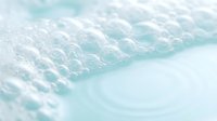 Soft white foam bubbles floating on crystal clear turquoise water surface creating peaceful spa-like atmosphere for wellness and relaxation concepts.