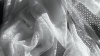 Ethereal monochrome fabric with delicate polka dot pattern creates flowing waves and soft folds, casting subtle shadows in black and white artistic composition.