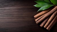 Fresh cinnamon sticks arranged with green bay leaves on dark wooden background, dramatic lighting creates rustic culinary atmosphere.
