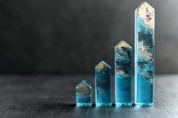 Ascending transparent resin houses with blue and gold details on dark background create modern minimalist business growth chart concept.