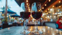 Two glasses of red wine on table with romantic bokeh lights in background, intimate restaurant setting creates atmospheric dining ambiance for date night or celebration.