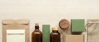 Eco-friendly packaging collection with brown glass bottles, kraft paper bags, green soap bars and natural materials for sustainable branding.