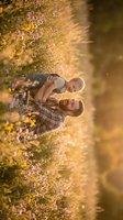 Happy Caucasian father holding baby son outdoors in autumn park with golden sunlight and colorful fall foliage creating warm family bonding moment.
