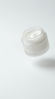 Open glass jar of white moisturizing cream on clean white background for skincare and beauty product advertising.