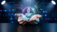 Hands holding holographic businessman avatar with digital interface and network connections for business technology concepts.
