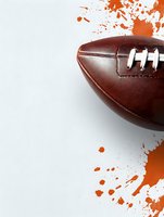 Brown leather football with white laces against white background with orange paint splatter frame, sports equipment close-up photography for athletic designs.